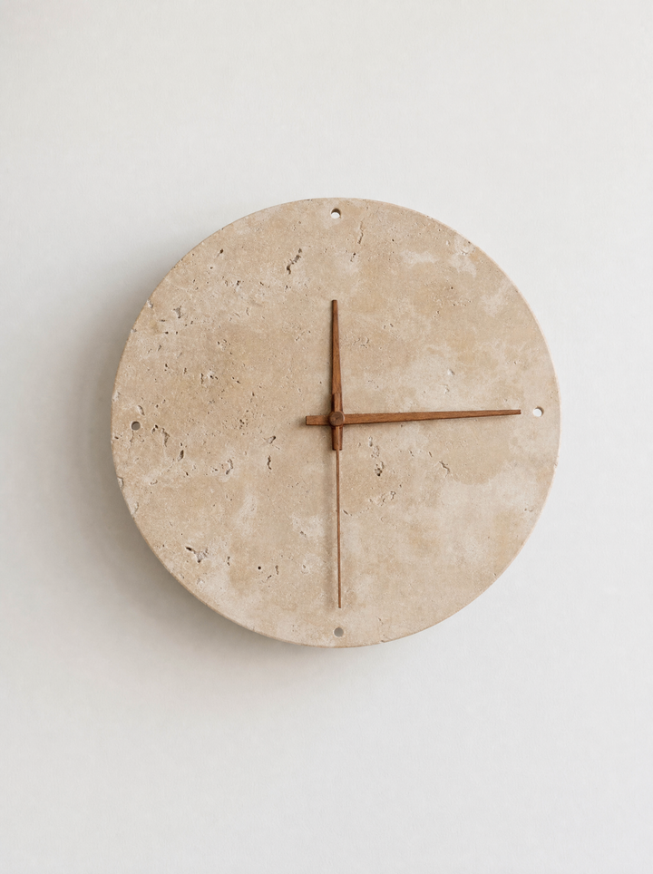 Adagio travertine wall clock, front view, light off, walnut hands and four round holes at the rim