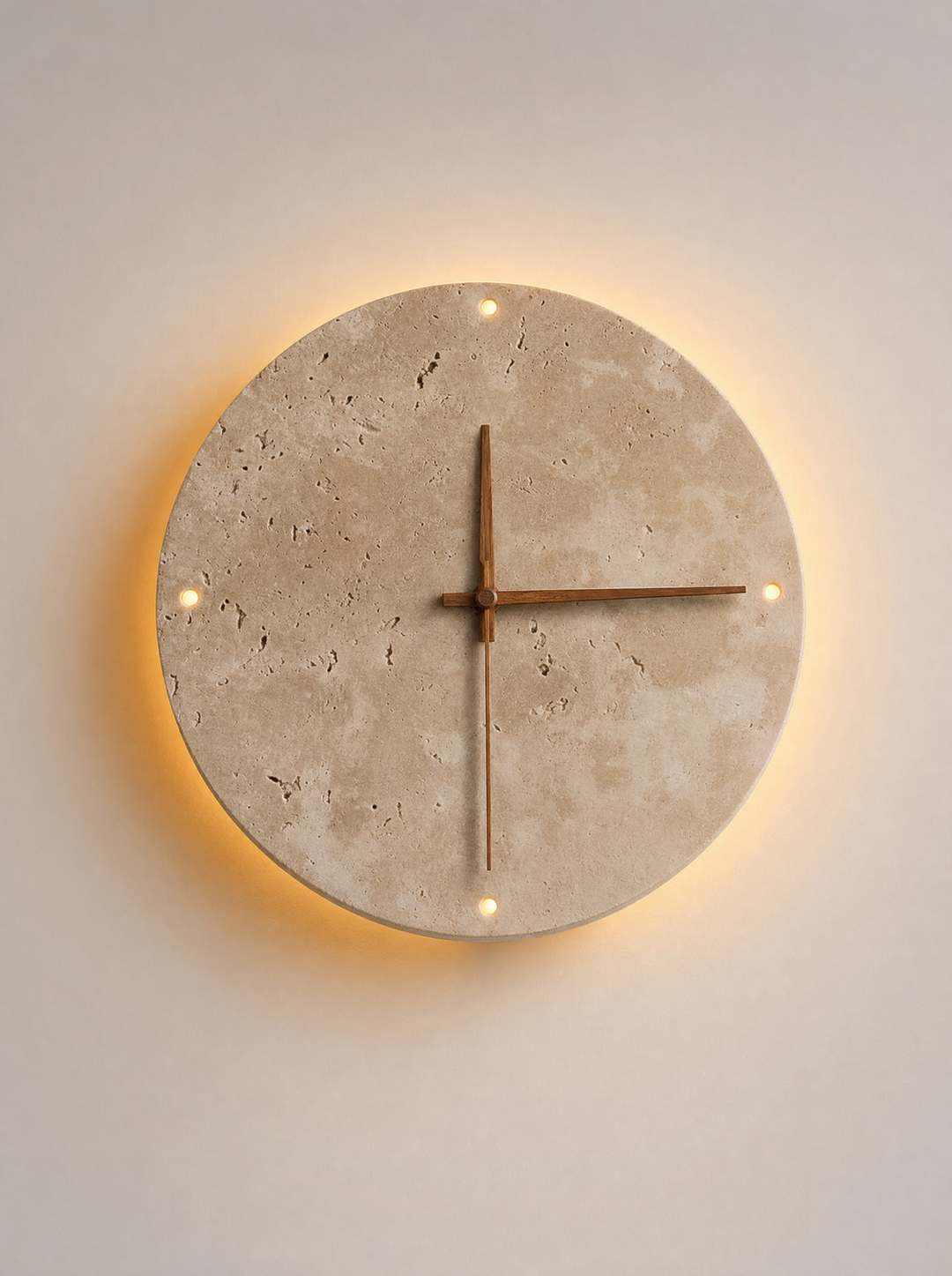 Adagio travertine wall clock, front view, light on, warm glow on the wall around the disc and through the four round holes