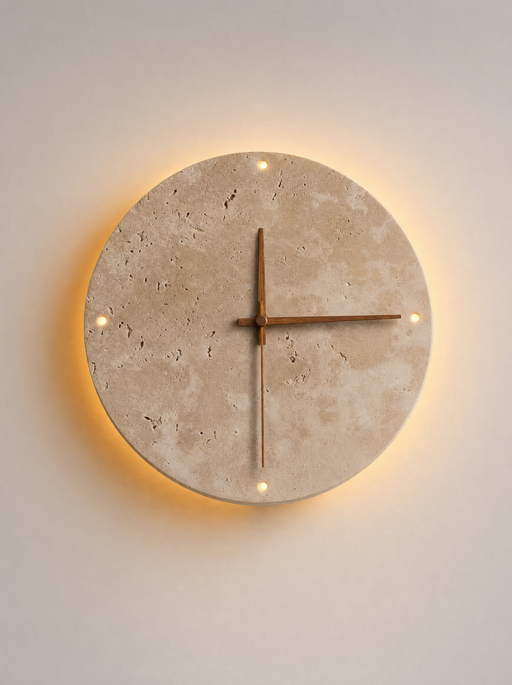 Adagio travertine wall clock, front view, light on, warm glow on the wall around the disc and through the four round holes