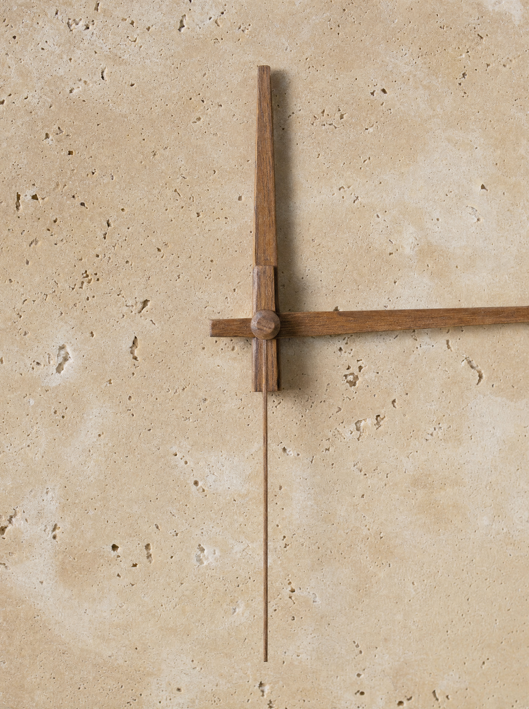 Macro close-up of the walnut hour and minute hands, slim second hand, and center spindle in the same walnut tone on the Adagio travertine face