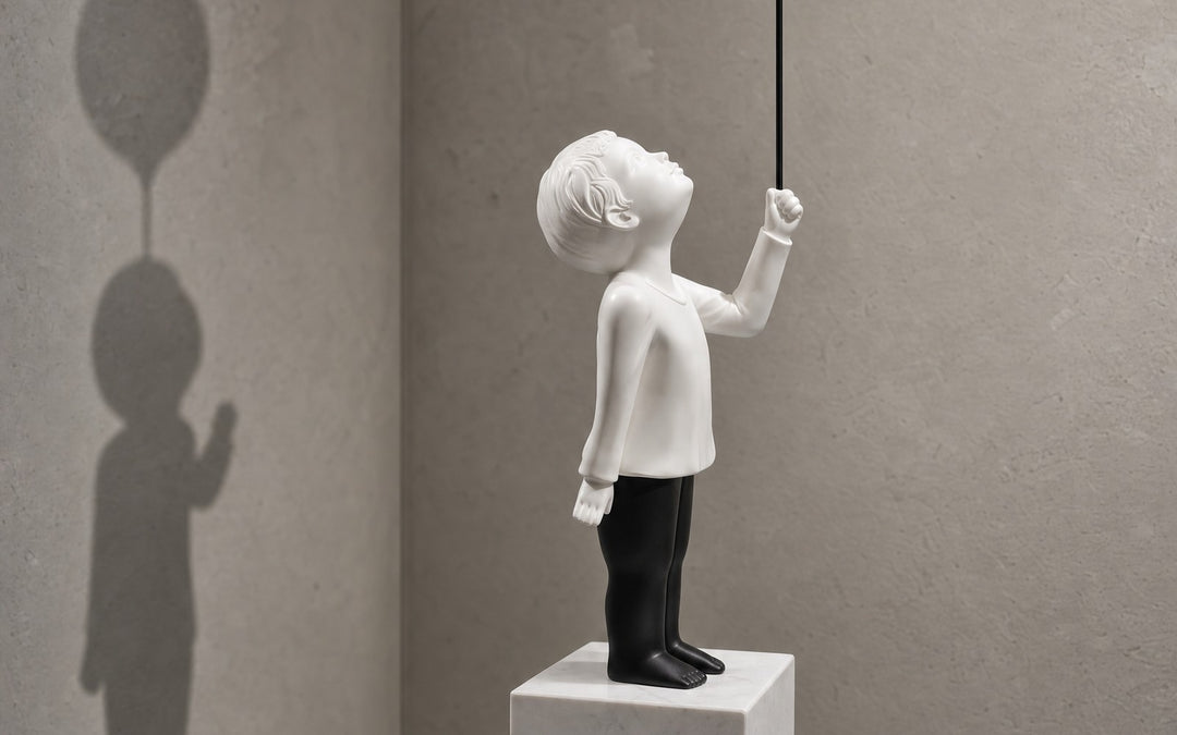 AeroCherub on a marble cube, its balloon's shadow on the wall behind