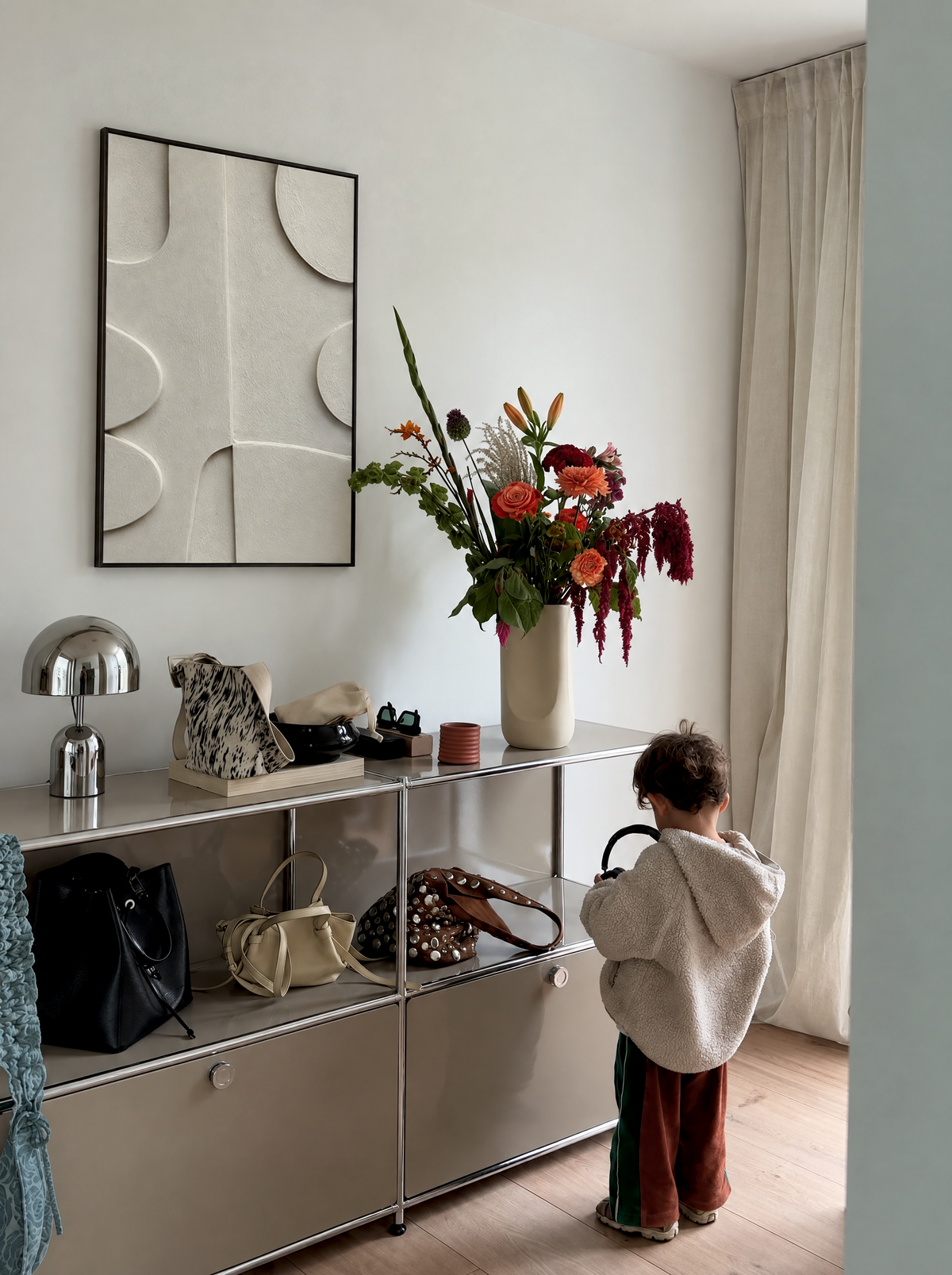 Curva Arco above a low metal cabinet with a vase of flowers