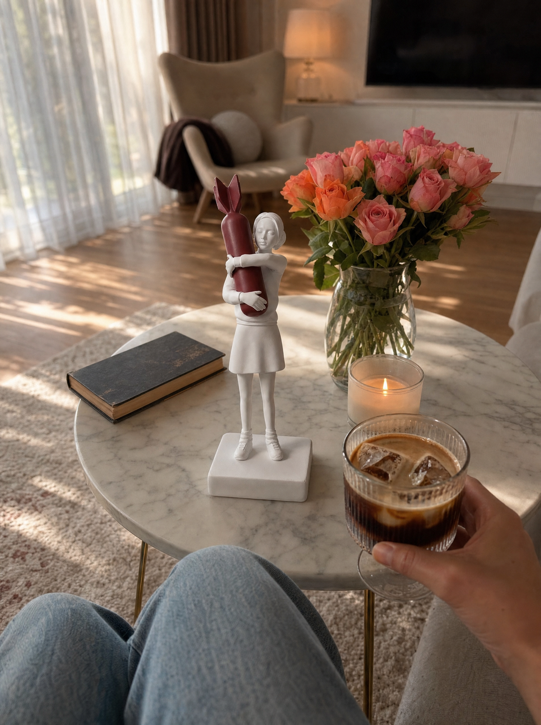 Disarm sculpture on a marble coffee table beside roses and a lit candle