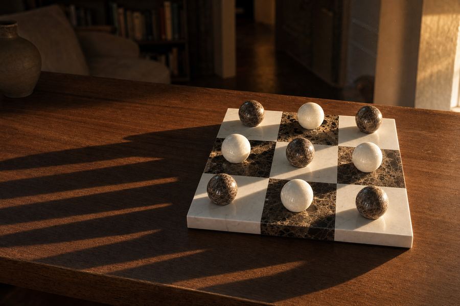 Lapilli board on a table in late-afternoon light, long shadow stripes crossing the surface.