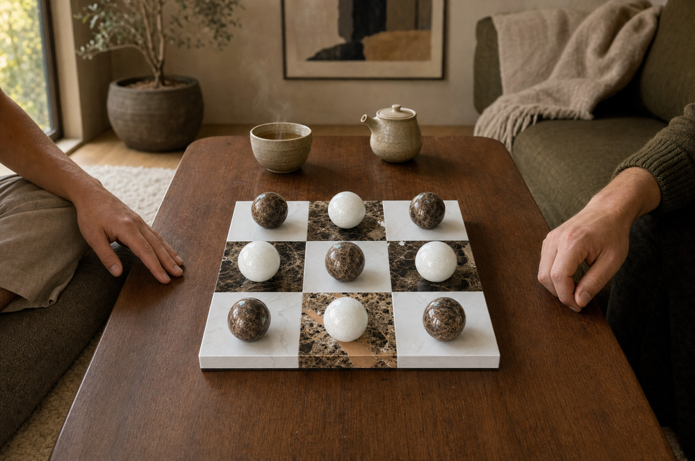 Lapilli marble board on a coffee table with tea, two people seated nearby.