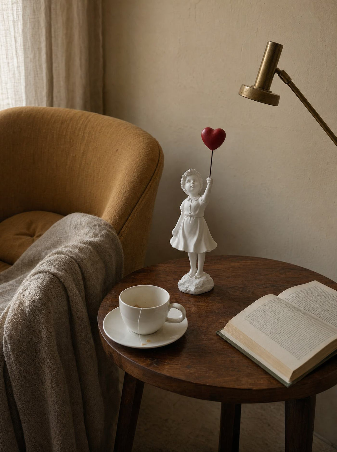 Ascend sculpture on a side table beside a mustard armchair and an open book