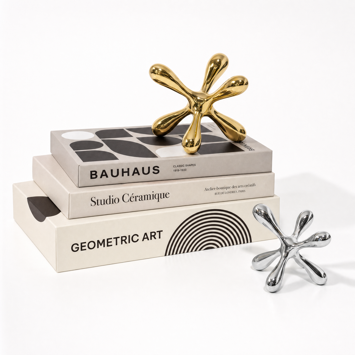 Gold Tali sculpture on a stack of three books beside a silver Tali sculpture