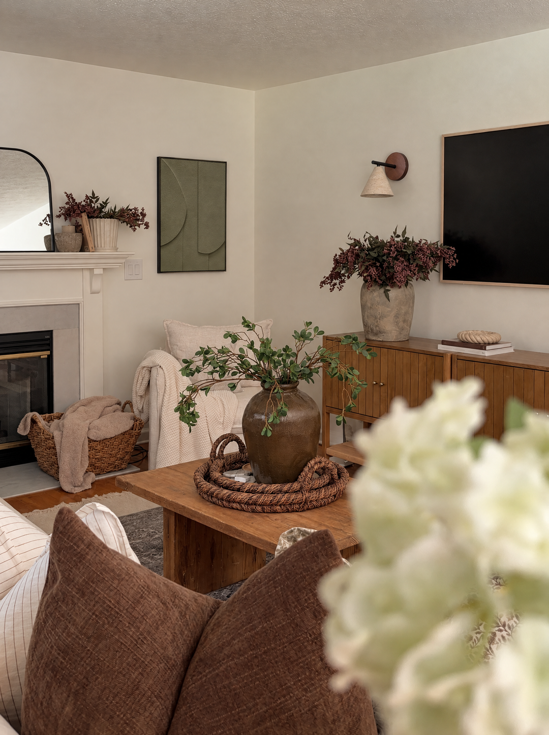 Tinta in Oliva hung on a cream wall beside a white fireplace in a family room