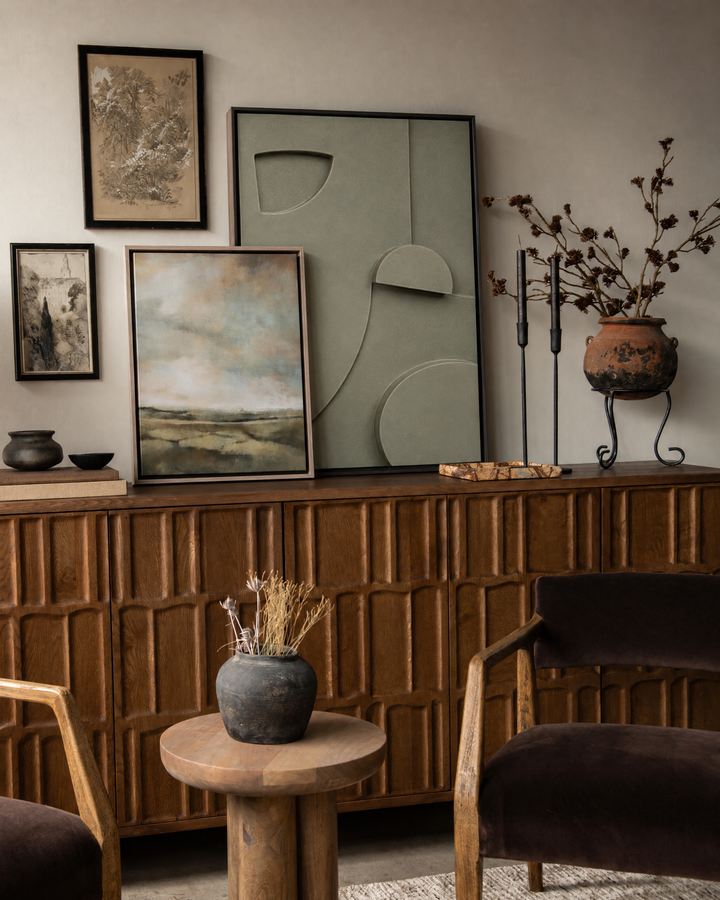 Tinta in Salvia leaning on a dark carved sideboard, layered with other frames against a warm greige wall
